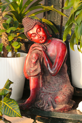 Resting Buddha. Buddhist figurine near pots with indoor plants. Vertical photo.
