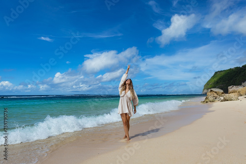 Young woman walks barefoot on the beach