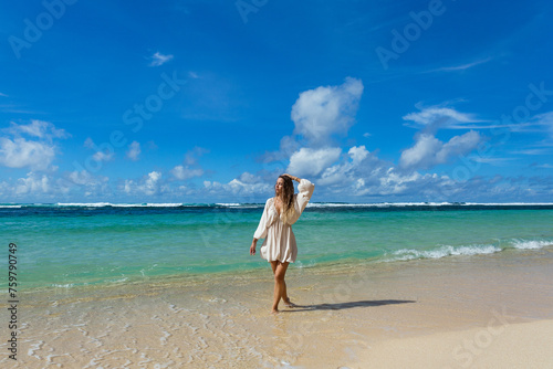 Beautiful young woman walking barefoot on the beach