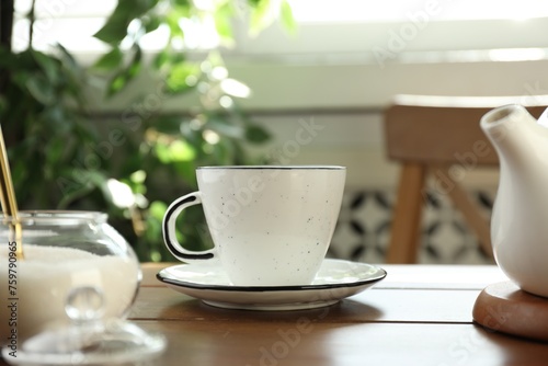 Cup of aromatic tea and sugar on wooden table indoors