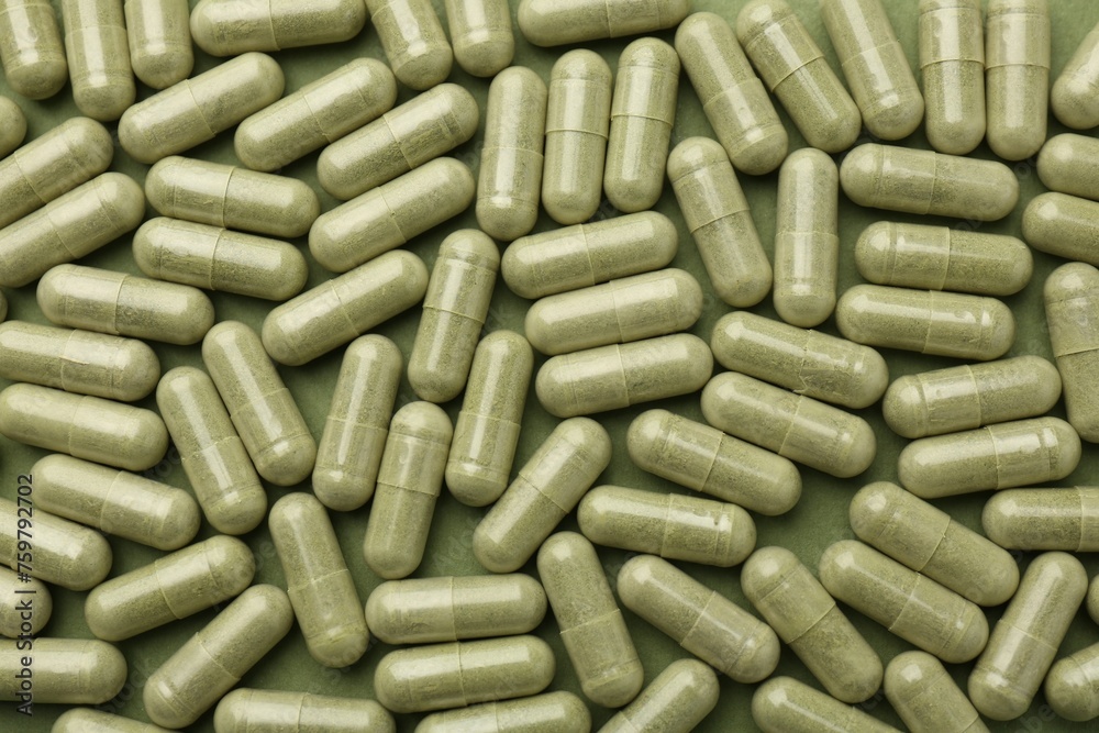 Vitamin capsules on olive background, flat lay