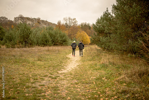 Two people walking in a field with trees in the background © Barbara
