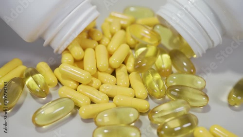 Tablets pills spilling from plastic pill bottle on natural background with selective focus. Pills for heart and vascular system support. 