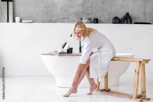 Mature woman applying varicose prevention treatment cream massaging legs