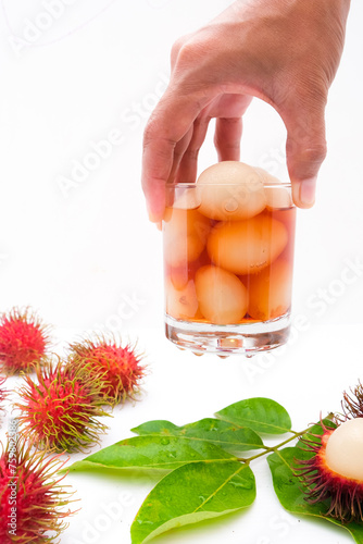 A man's hand holds a glass containing rambutan fruit syrup photo