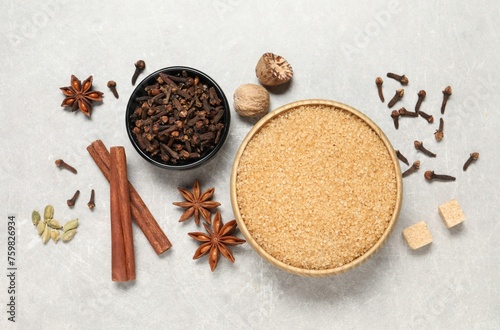 Different spices in bowls and nuts on light gray textured table, flat lay