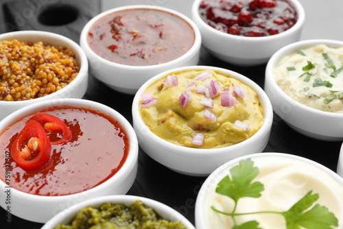 Different tasty sauces in bowls on board, closeup