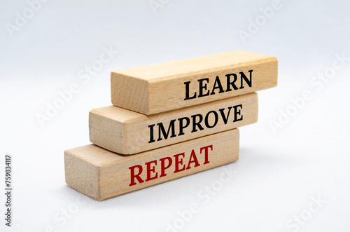Learn, Improve and Repeat text on wooden blocks with white cover background. Improvement and development concept photo