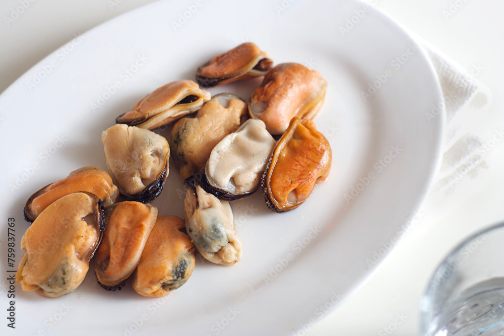 Mussels lie in a white plate on a white table Mussels lie in a white plate on a white table