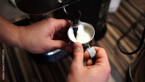 Bartender froths milk in the milk jug with the nozzle of a coffee machine. High quality 4k footage photo