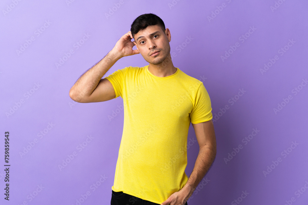 Young Colombian man isolated on purple background having doubts Young Colombian man isolated on purple background having doubts