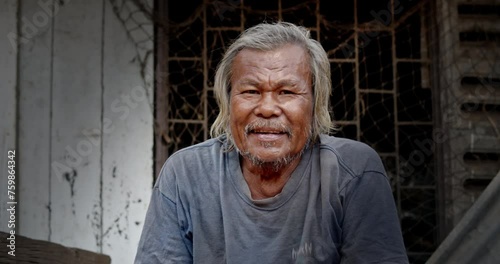 A smiling Asian man who is a homeless ragpicker or has a career collecting garbage and selling it, live in a abandoned house at a slum village. photo