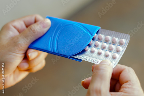 A woman holds her birth control pill. The medication is a pill that contains a combination of hormones, usually synthetic estrogen and progesterone, that inhibit ovulation.