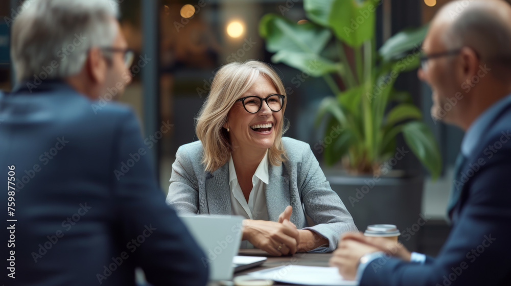 A smiling woman holding a pen is enjoying a light-hearted moment with her colleagues in a sunlit, modern office space. A smiling woman holding a pen is enjoying a light-hearted moment with her colleagues in a sunlit, modern office space.