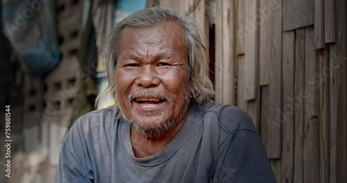 A smiling Asian man who is a homeless ragpicker or has a career collecting garbage and selling it, live in a abandoned house at a slum village. photo