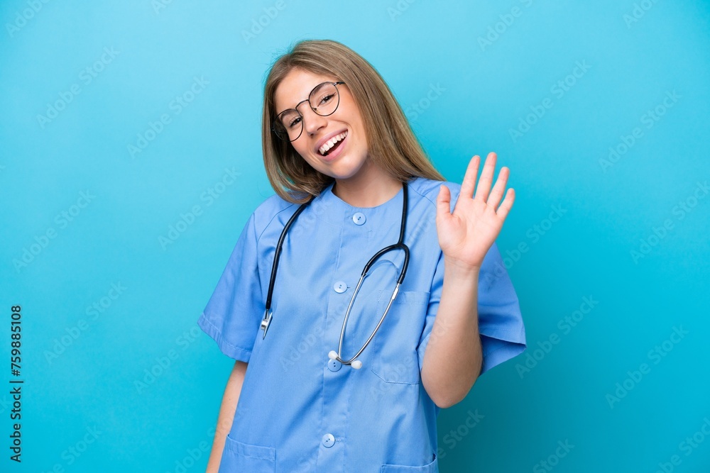 Young surgeon doctor woman isolated on blue background saluting with hand with happy expression Young surgeon doctor woman isolated on blue background saluting with hand with happy expression