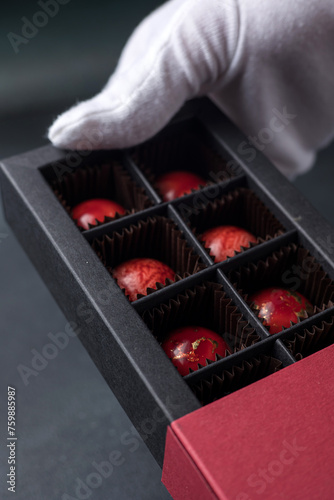 Box of chocolate candies in the hands of a pastry chef.