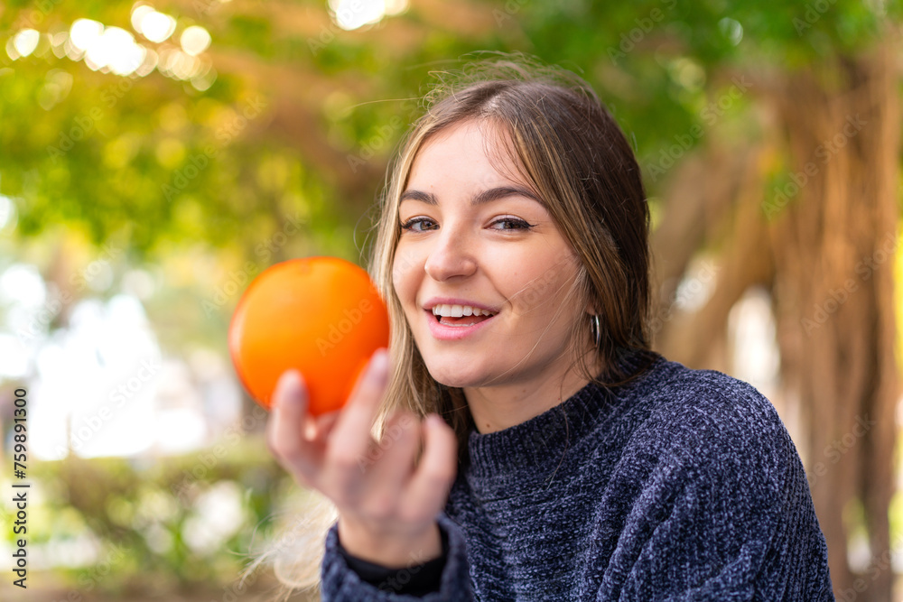 Young pretty Romanian woman holding an orange at outdoors Young pretty Romanian woman holding an orange at outdoors