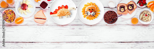 Fun child theme breakfast top border with an assortment of animal themed food. Overhead view on a white wood banner background. Pancakes, oatmeal, toast, fruit and cereal.