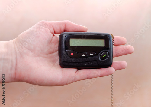 Obraz na plátně pager in close-up, an old retro communication device, in female hand on a beige