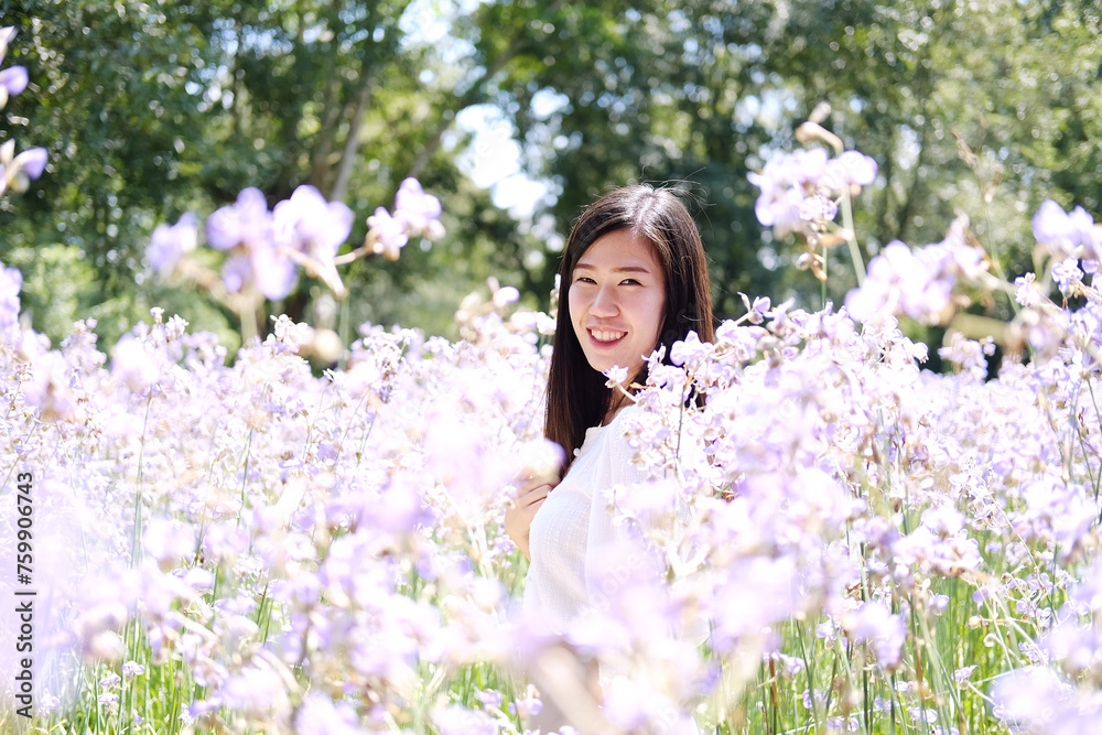 Beautiful Asian woman is smiling and relaxing in blooming purple Murdannia giganteum flowers field Beautiful Asian woman is smiling and relaxing in blooming purple Murdannia giganteum flowers field