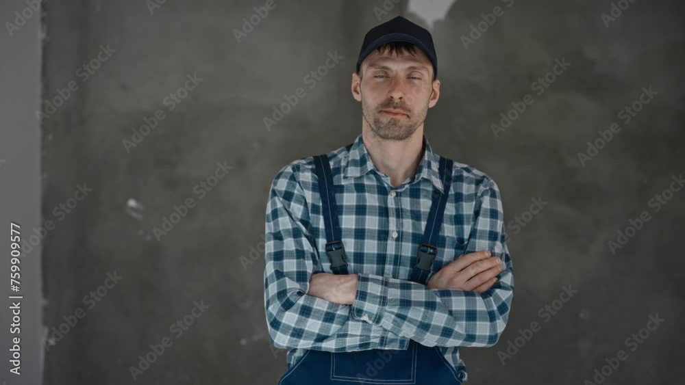 A man in a plaid shirt and suspenders is standing with his arms crossed A man in a plaid shirt and suspenders is standing with his arms crossed