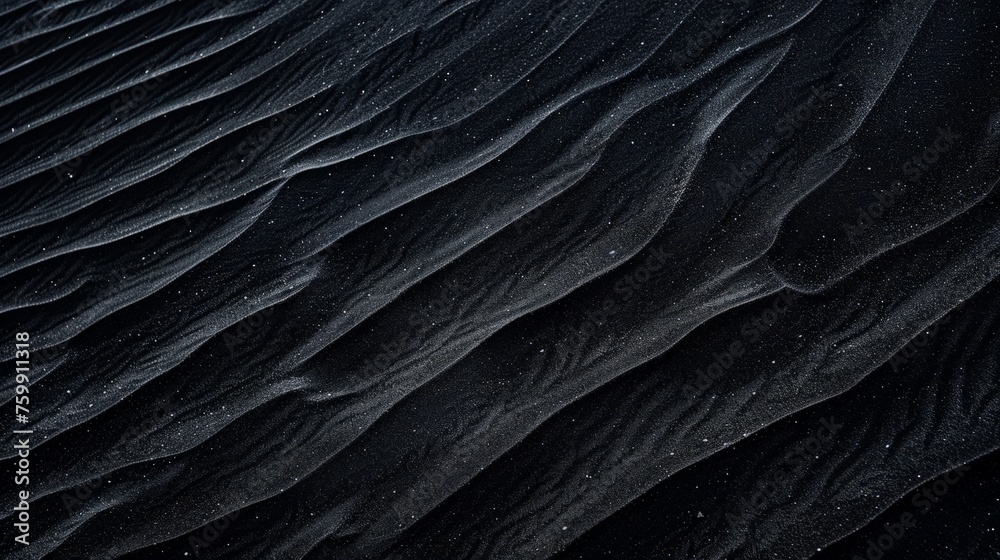 Obraz premium Detailed view of a dark-hued sand dune, showcasing its texture and shape in close proximity.