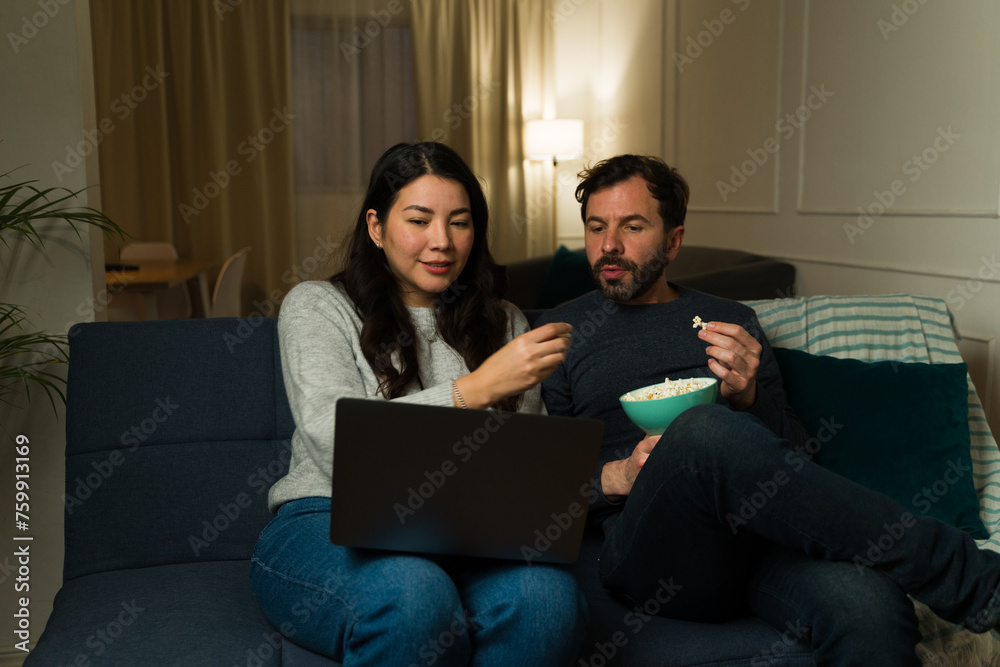 Happy couple relaxing watching a movie on the laptop