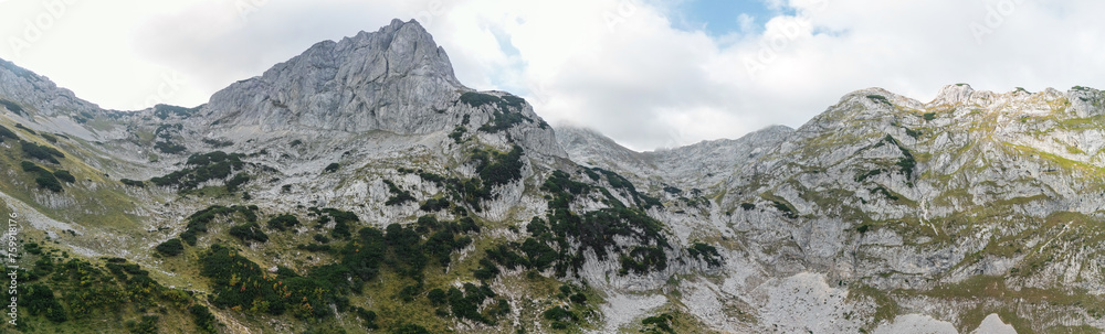 Drone shot of mountain peaks with rocky slopes, cliffs and scattered trees, Durmitor, Montenegro