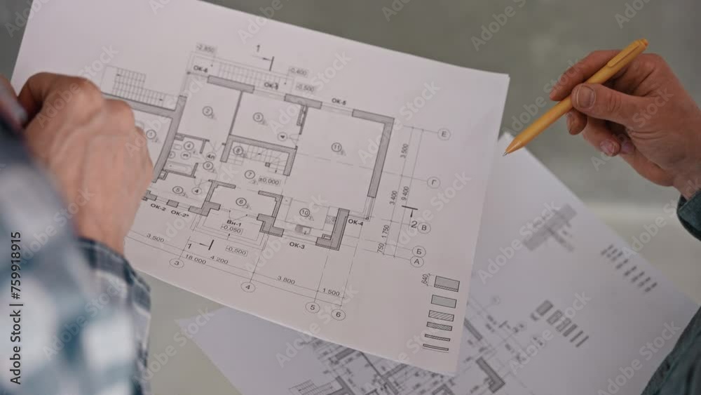 An engineer and a builder discuss a house project based on detailed drawings. Work on a construction site. Developer