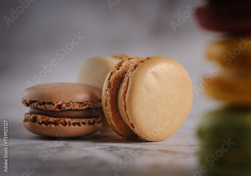 Close up of 3 brown toned macaroons against a light background with some macaroons in the foreground.
