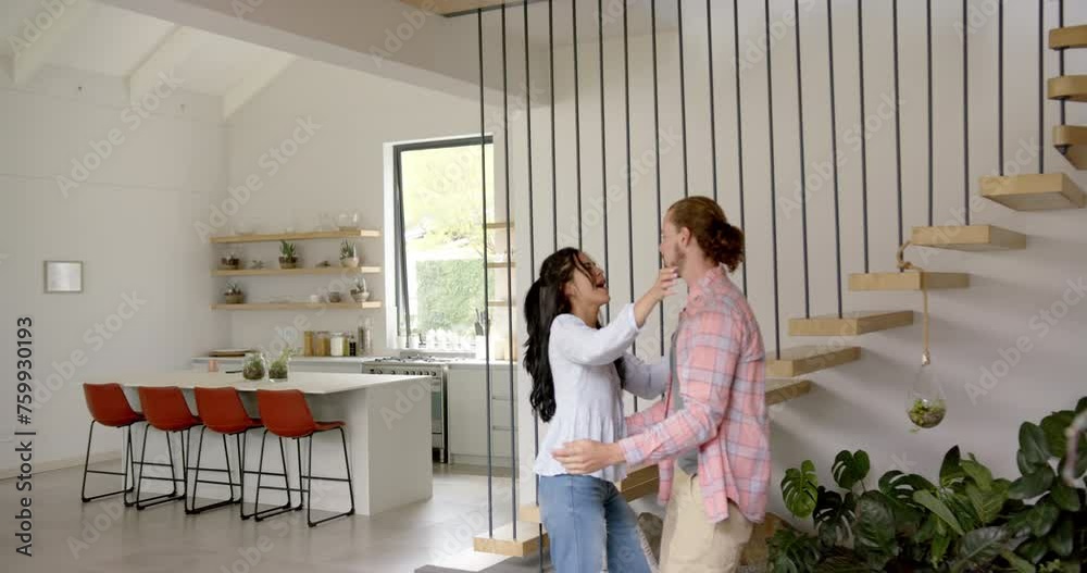 A young biracial couple is sharing a playful moment in a modern kitchen at home, copy space A young biracial couple is sharing a playful moment in a modern kitchen at home, copy space