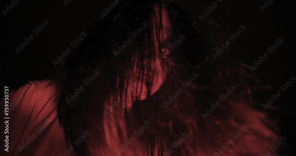 A woman ghost with hair over their face with wind blowing illuminated by a red light creating a haunting effect. Halloween holiday A woman ghost with hair over their face with wind blowing illuminated by a red light creating a haunting effect. Halloween holiday