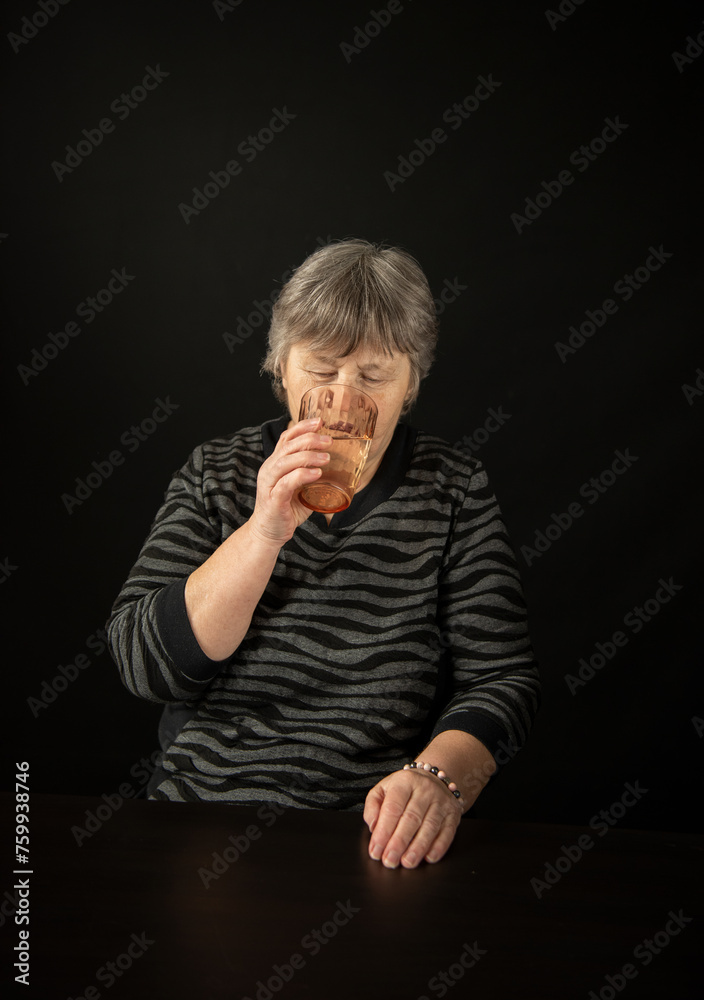 Elderly lady is drinking a water.