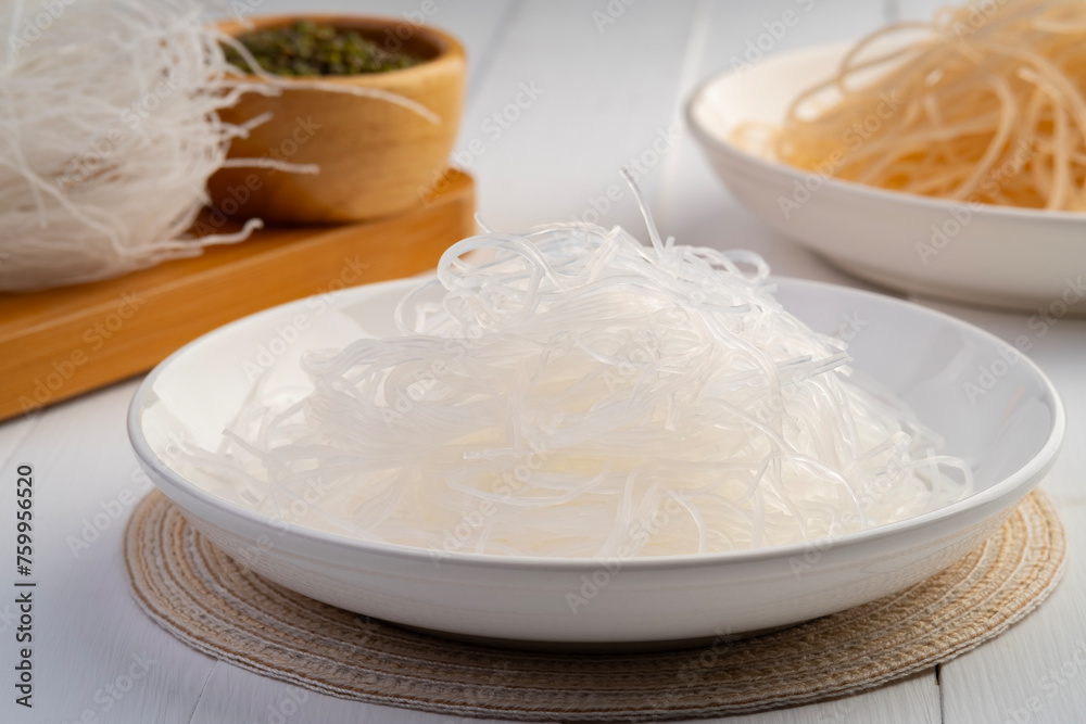 Fresh Glass Noodle in white plate with Dry Glass Noodle on wooden plate (Transparent bean vermicelli).