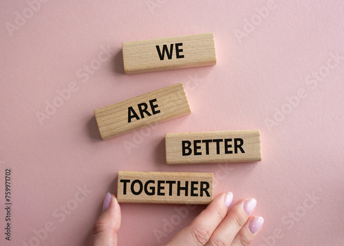 We are better together symbol. Wooden blocks with words We are better together. Beautiful pink background. Businessman hand. We are better together concept. Copy space.