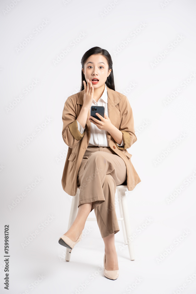 Full body image of young Asian businesswoman sitting and using phone on white background Full body image of young Asian businesswoman sitting and using phone on white background