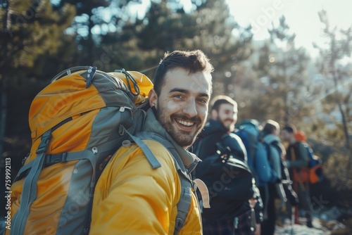 A man with a backpack smiles cheerfully as he poses for a camera, ready for a hiking adventure © pham