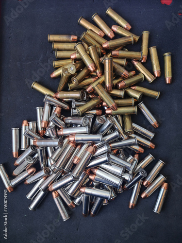 Two piles of .38 special caliber bullets with a fullmetal jacket tip, some are silver-colored and the others gold-colored. They are on top of a cloth, final cleaning of the recharging process photo