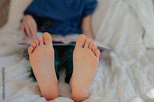 Boy is reading in the bedroom on the bed