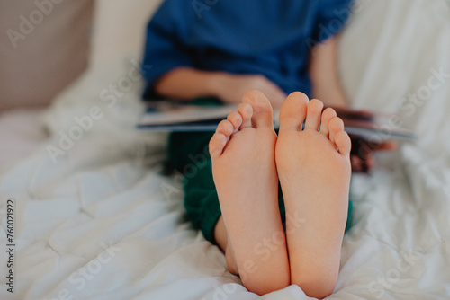 Boy is reading in the bedroom on the bed