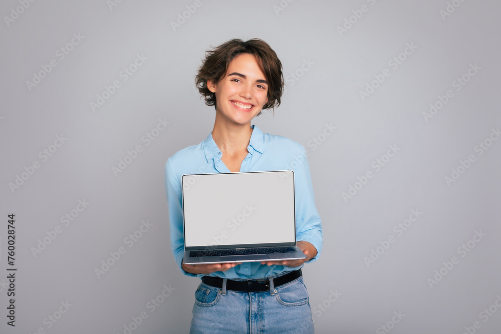 Close up image of smiling beautiful modern business woman in smart casual wear shows laptop in hands with blank screen. Copy space for your apps and adverts your firm Close up image of smiling beautiful modern business woman in smart casual wear shows laptop in hands with blank screen. Copy space for your apps and adverts your firm