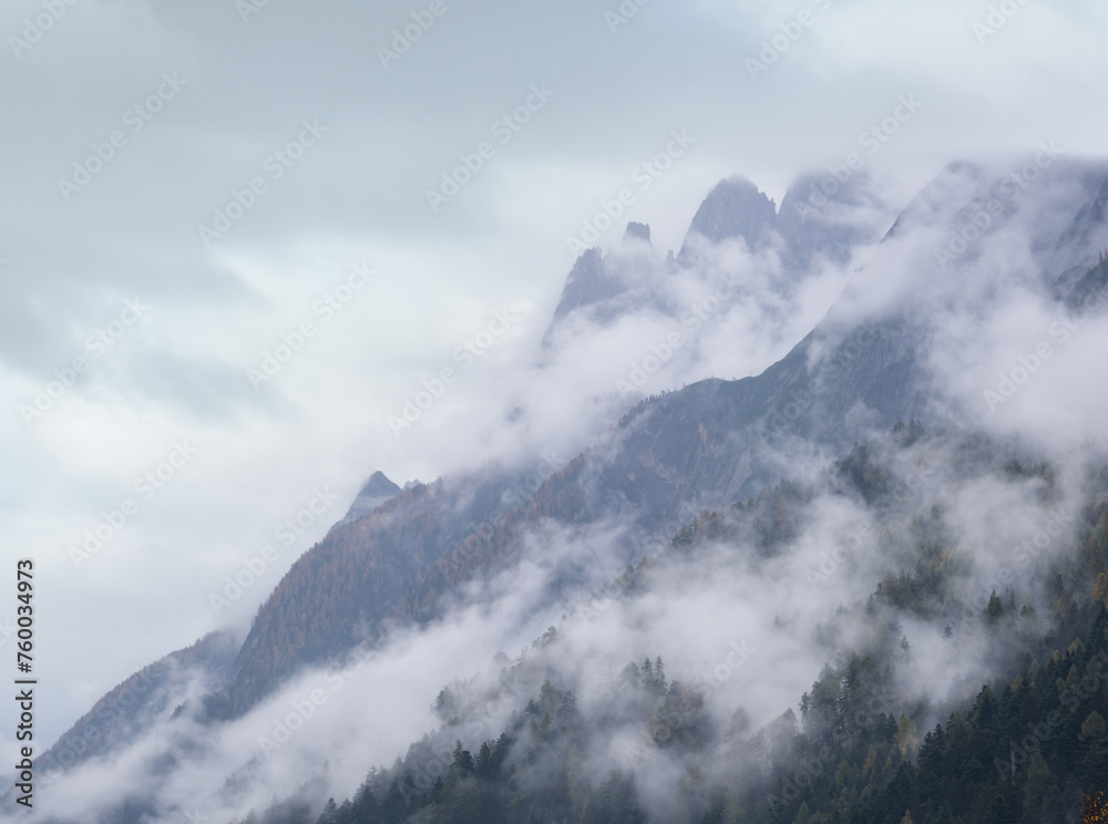 Mystic cloudy and foggy autumn alpine mountain slopes scene. Austrian Lienzer Dolomiten Alps.