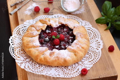 Raspberry cake pie on a wooden table. Summer homemade crunchy pie with fresh berries and mint leaves. Slow living concept. Family breakfast. © Foodie Studio