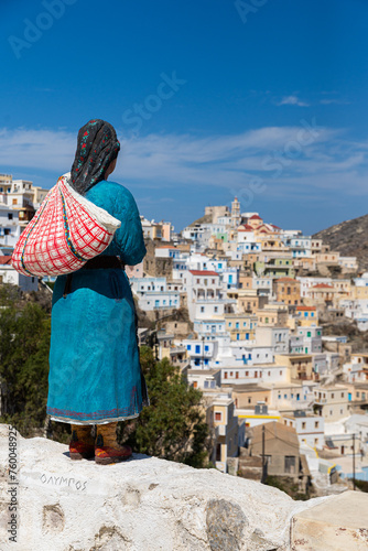 Statue of a greek woman in a traditional outfit looking over Olympos, Karpathos, Greece. photo