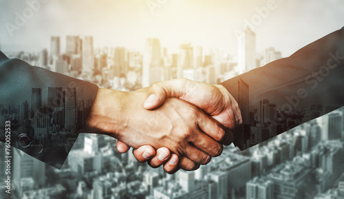 Double exposure image of business people handshake on city office building in background showing partnership success of business deal. Concept of corporate teamwork, trust partner and work agreement. photo