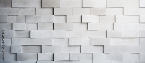 A white wall adorned with a repetitive pattern of grey rectangles in a symmetric and parallel layout. The rectangles give a subtle texture to the beige building material