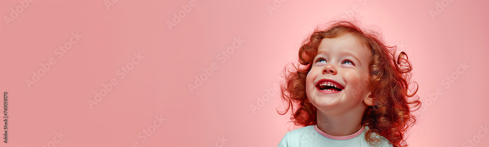 A gleeful child with curly red hair laughs heartily against a rosy pink backdrop A gleeful child with curly red hair laughs heartily against a rosy pink backdrop