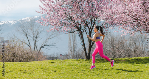 Sportive girl running in park on spring day in front of blossom
