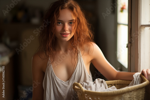 Young pretty brunette girl at indoors holding clothes basket